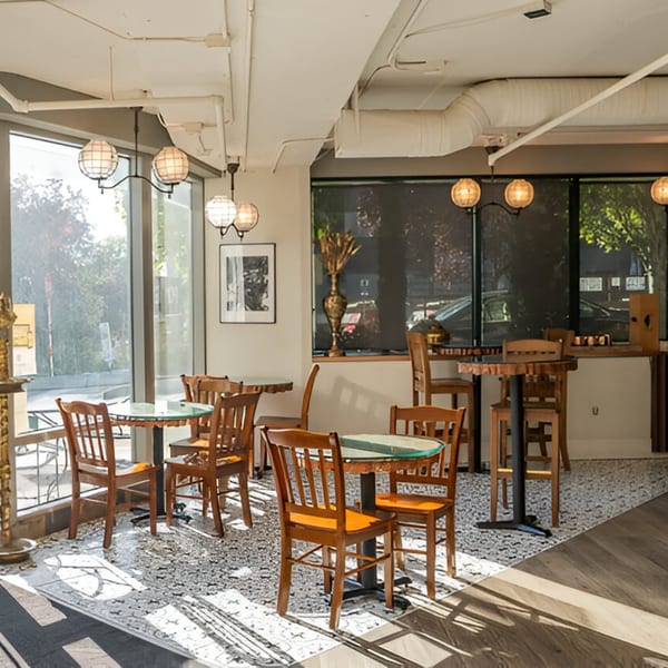 Bright, modern Far Eats Cafe interior with wooden tables and chairs, large windows, and decorative lighting.