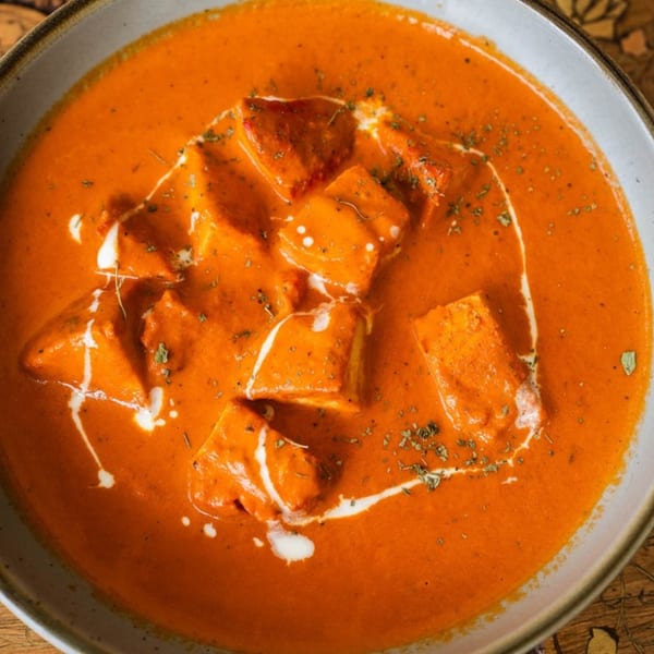 Close-up of Far Eats Cafe's Indian paneer butter masala, garnished with cream and herbs.